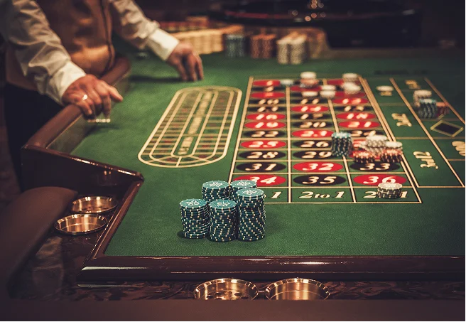 Une table de roulette classique avec des piles de jetons de casino dans un cadre de casino élégant.
